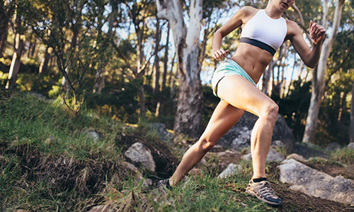 A young woman running on an outdoor trail in the woods