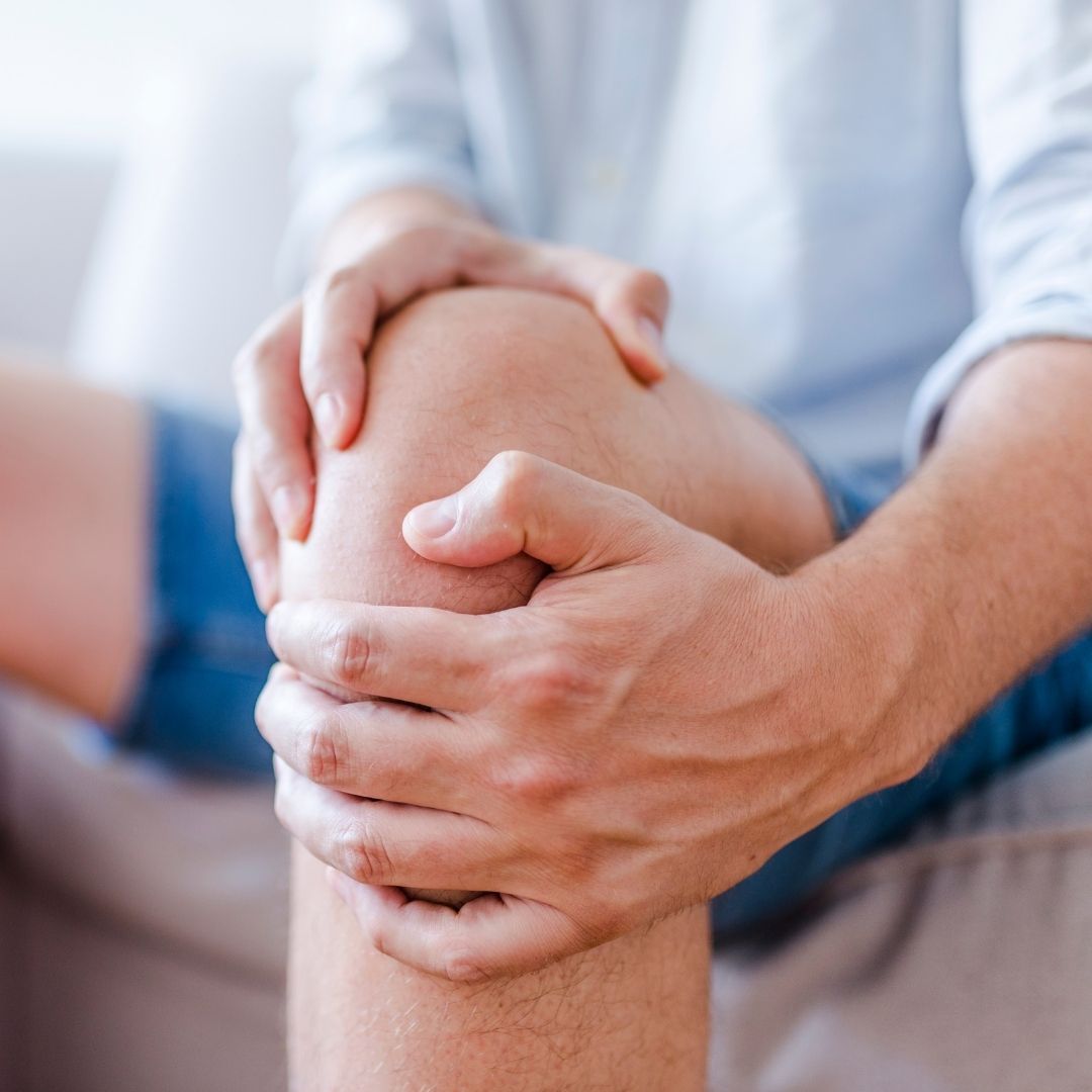 Man holding his knee while sitting on couch