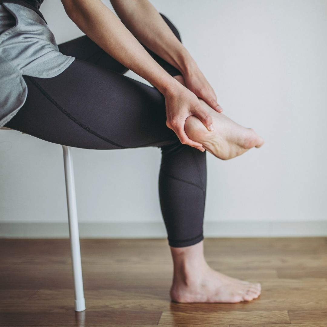 Woman sitting in chair holding heel of her foot