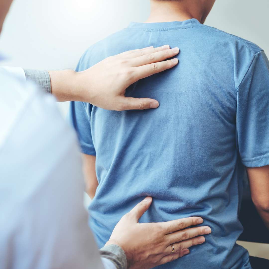 physical therapist with hands on patient's back