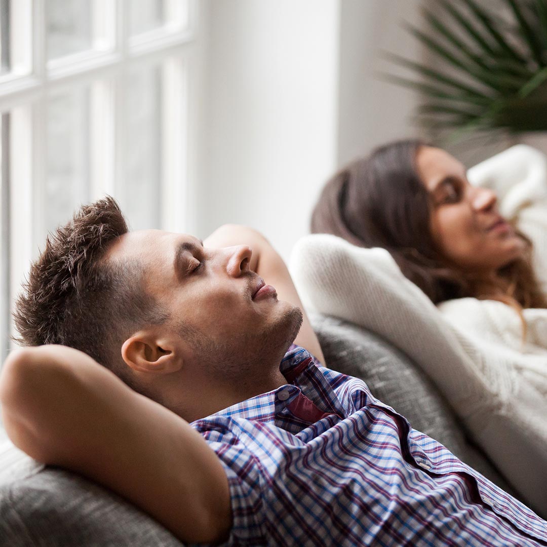 happy man and woman relaxing on their sofa