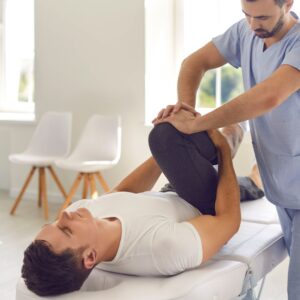Therapist pushes patient's bent knee during therapy session