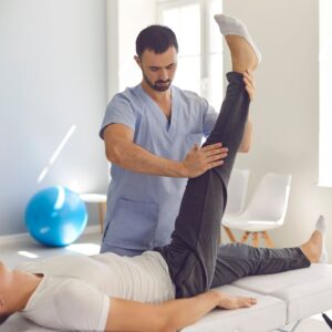 Therapist stretches patient's leg on massage table