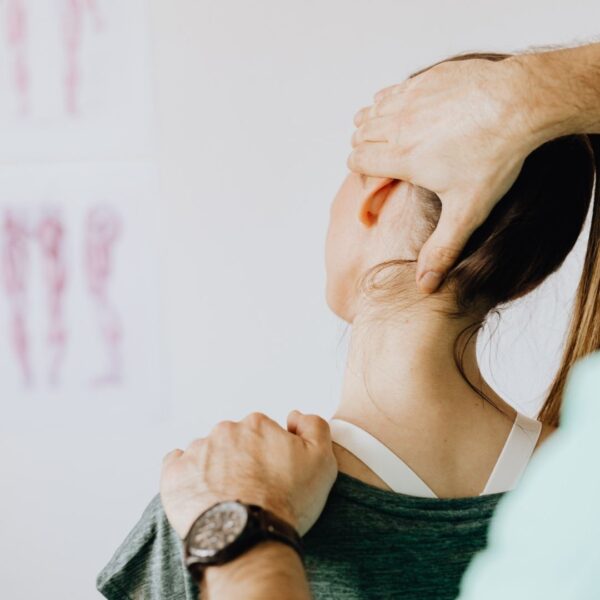 Close-up of a chiropractor's hands providing a gentle cervical adjustment to a patient in a wellness clinic.